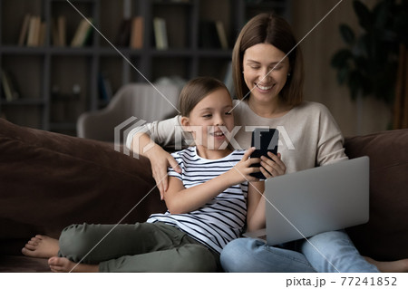Happy young mother and little daughter use gadgets Happy young mother and little daughter use gadgets 77241852