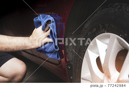 Human hand was cleaning to dirty car body with a microfiber cloth 77242984