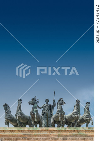 Statues of 6 horses and Goddess Victoria at the top of Triumphal Arch called Arch of Peace (Porta Sempione) in Milan historical downtown, Sempione Park, Italy, with copy space.. Statues of 6 horses and Goddess Victoria at the top of Triumphal Arch called Arch of Peace (Porta Sempione) in Milan historical downtown, Sempione Park, Italy, with copy space.. 77243432