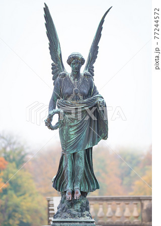 Statue of ancient beautiful winged angel in downtown park of Potsdam in beginning of Autumn at sunset, Germany Statue of ancient beautiful winged angel in downtown park of Potsdam in beginning of Autumn at sunset, Germany 77244572