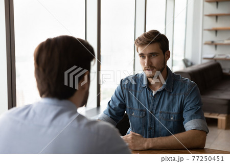 Young Caucasian businessmen talk discuss collaboration at meeting Young Caucasian businessmen talk discuss collaboration at meeting 77250451