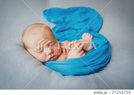 newborn baby sleeps wrapped in a blanket newborn baby sleeps wrapped in a blanket 77250759