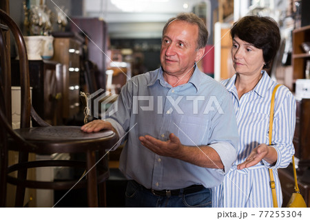 Adult woman with husband are buying antique armchair Adult woman with husband are buying antique armchair 77255304