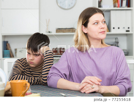 Sad son and unhappy mom sitting after quarrel in home Sad son and unhappy mom sitting after quarrel in home 77255618