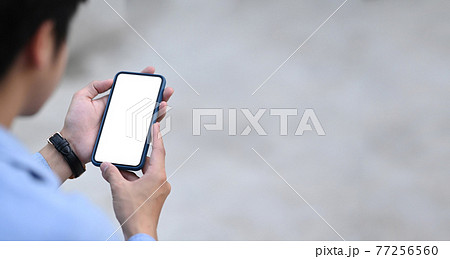 Cropped shot of young man holding mobile phone with white blank screen. 77256560