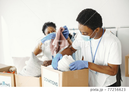 African volunteers in protective masks and gloves pack boxes African volunteers in protective masks and gloves pack boxes 77256623