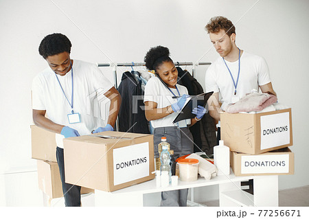 Two boys and a girl volunteers pack humanitarian aid Two boys and a girl volunteers pack humanitarian aid 77256671
