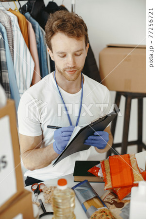Volunteer guy packs boxes with a humanitarian help Volunteer guy packs boxes with a humanitarian help 77256721