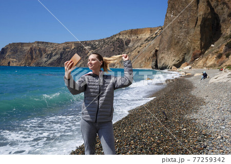 a young woman takes a selfie by the ocean 77259342