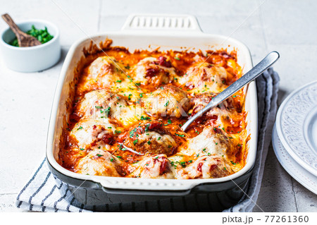 Baked cheese meatballs casserole with tomato sauce in the oven dish. 77261360