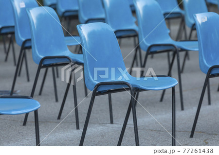 Rows and columns of nondescript blue plastic chairs, consecutive, arranged in a line, at similar intervals of space, facing the same place. Retiro Park, Madrid, Spain. Rows and columns of nondescript blue plastic chairs, consecutive, arranged in a line, at similar intervals of space, facing the same place. Retiro Park, Madrid, Spain. 77261438