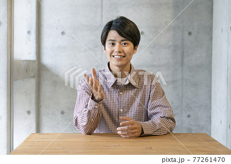 カメラ目線の笑顔の若い男性 77261470