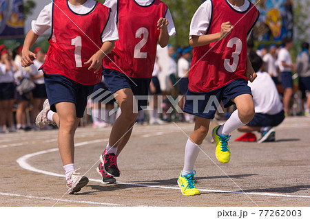 体育祭でゼッケンをつけてトラックのコーナーを走る男子生徒 77262003