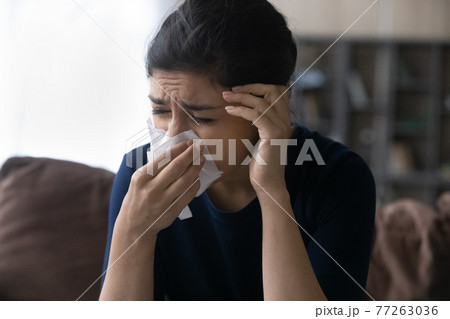 Close up unhappy sick Indian woman blowing nose, catch cold Close up unhappy sick Indian woman blowing nose, catch cold 77263036