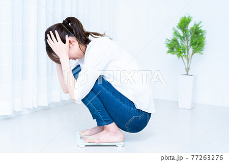 体重計に乗ってショックを受ける女性 体重計に乗ってショックを受ける女性 77263276