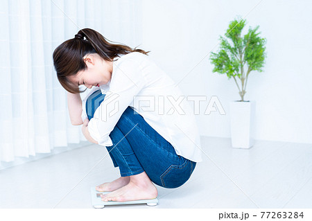 体重計に乗ってショックを受ける女性 体重計に乗ってショックを受ける女性 77263284