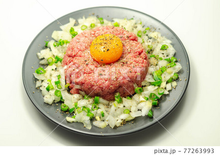 Beef steak tartare with raw egg yolk and onion with chive 77263993