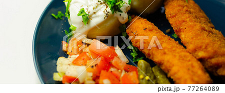 Breaded and herbed chicken breast fillet served with mashed potatoes,  tomato salad with onions and gherkin 77264089