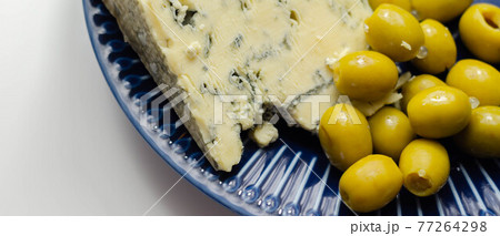 Full fat soft blue veined cheese and pickled olives stuffed garlic on the blue plate 77264298