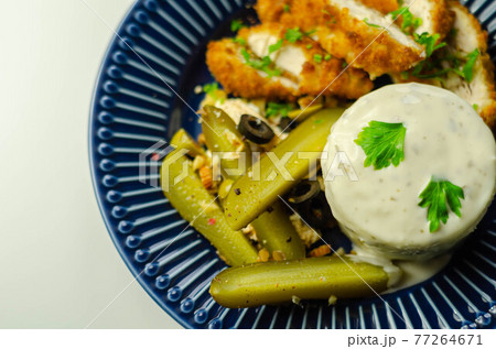Breaded chicken breast fillet served with mashed  potatoes  and  gherkin  with olives 77264671