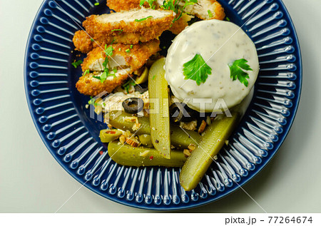 Breaded chicken breast fillet served with mashed  potatoes  and  gherkin  with olives 77264674