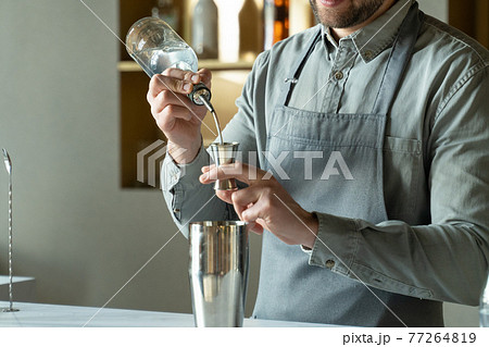 Close-up professional bartender pours rum into a shaker, making a classic cocktail in a modern trendy bar. 77264819