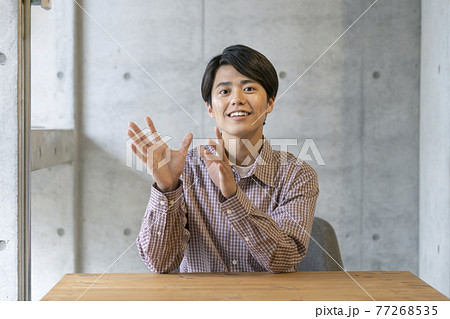 カメラ目線で話す笑顔の若い男性 77268535