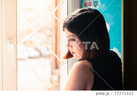 beautiful young brunette woman stands thoughtfully at the window beautiful young brunette woman stands thoughtfully at the window 77271322