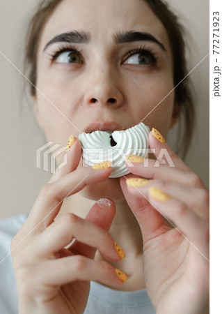 Young woman eating marshmallow. Pretty caucasian woman smiling. Sincere emotions. facial expressions. Soft focus. Healthy teeth concept 77271923