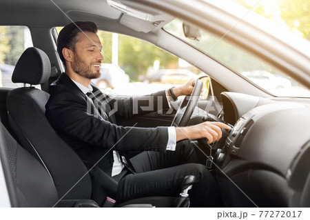 Handsome businessman driving car to airport, turning on music 77272017