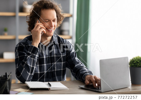 Cheerful Businessman Talking On Cellphone Sitting At Workplace In Office 77272257
