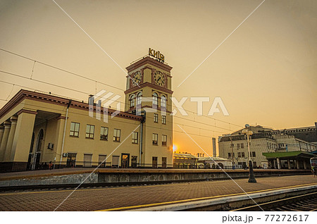 Suburban railway station building with clock tower and Kyiv-Pasazhyrskyi central railway station in the rays of the rising sun. Kyiv, Ukraine 77272617