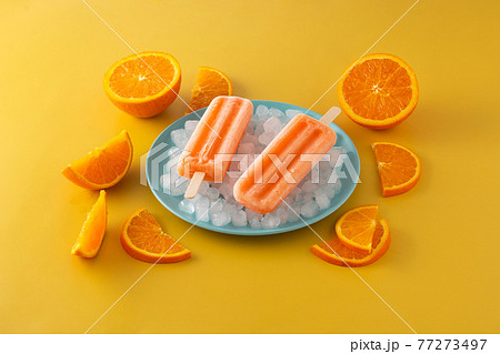 Orange popsicles on blue plate 77273497