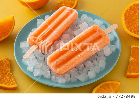 Orange popsicles on blue plate Orange popsicles on blue plate 77273498
