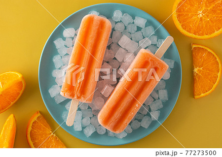 Orange popsicles on blue plate Orange popsicles on blue plate 77273500