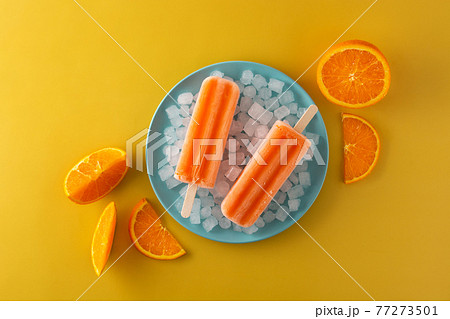 Orange popsicles on blue plate 77273501