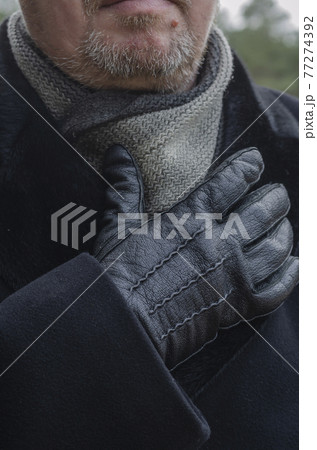A cropped photo of a middle-aged man wearing a black coat and gloves. A cropped photo of a middle-aged man wearing a black coat and gloves. 77274392