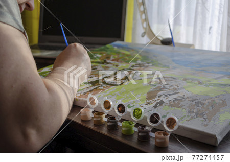 Active leisure at home, creative hobby concept. Hands of an adult woman painted with brush picture of numbers. Active leisure at home, creative hobby concept. Hands of an adult woman painted with brush picture of numbers. 77274457