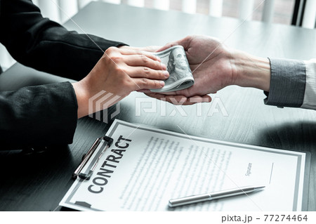 Business woman giving bribe money to businessman to bribing deal contract in a corruption, Illegal, dishonest and scam 77274464