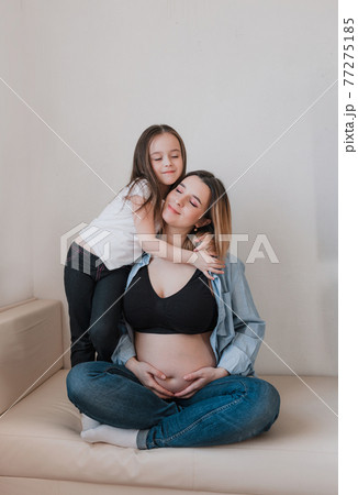 Baby girl and pregnant mother loving little sister next to mother's belly Baby girl and pregnant mother loving little sister next to mother's belly 77275185
