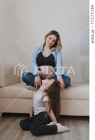 Baby girl and pregnant mother loving little sister next to mother's belly Baby girl and pregnant mother loving little sister next to mother's belly 77275186