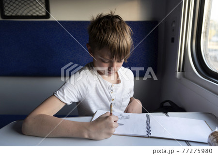 Schoolboy drawing at table in compartment train. Teaching child while traveling. Schoolboy drawing at table in compartment train. Teaching child while traveling. 77275980