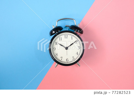 Black vinatge alarm clock with pink and blue background. 77282523