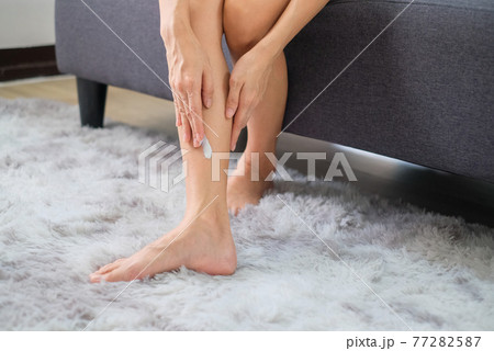 Woman applying natural cream, Woman moisturizing her leg with cosmetic cream with copy space. 77282587