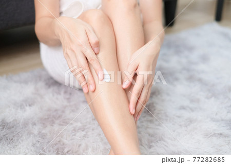 Woman applying natural cream, Woman moisturizing her leg with cosmetic cream with copy space. 77282685