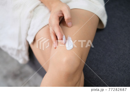 Woman applying natural cream, Woman moisturizing her thigh with cosmetic cream with copy space. 77282687