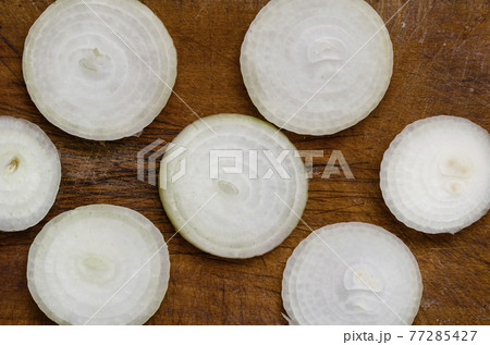 Raw bulb sliced with rings on wooden chopping board. 77285427