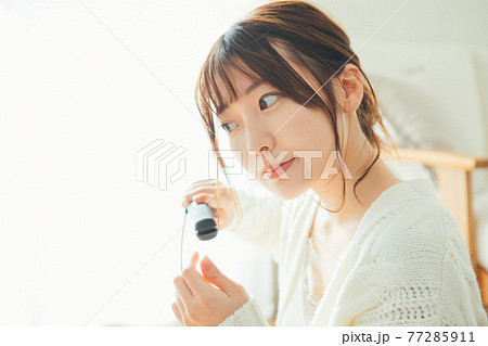 ヘアアイロンを使う若い女性 77285911