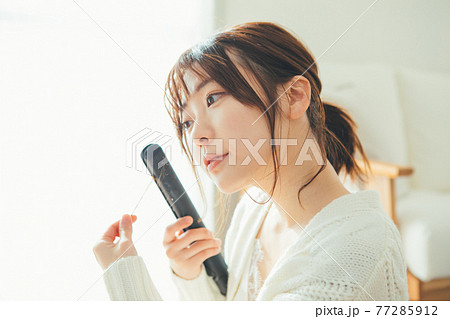 ヘアアイロンを使う若い女性 77285912