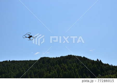 山を背景に大空を舞うドローン 77286015
